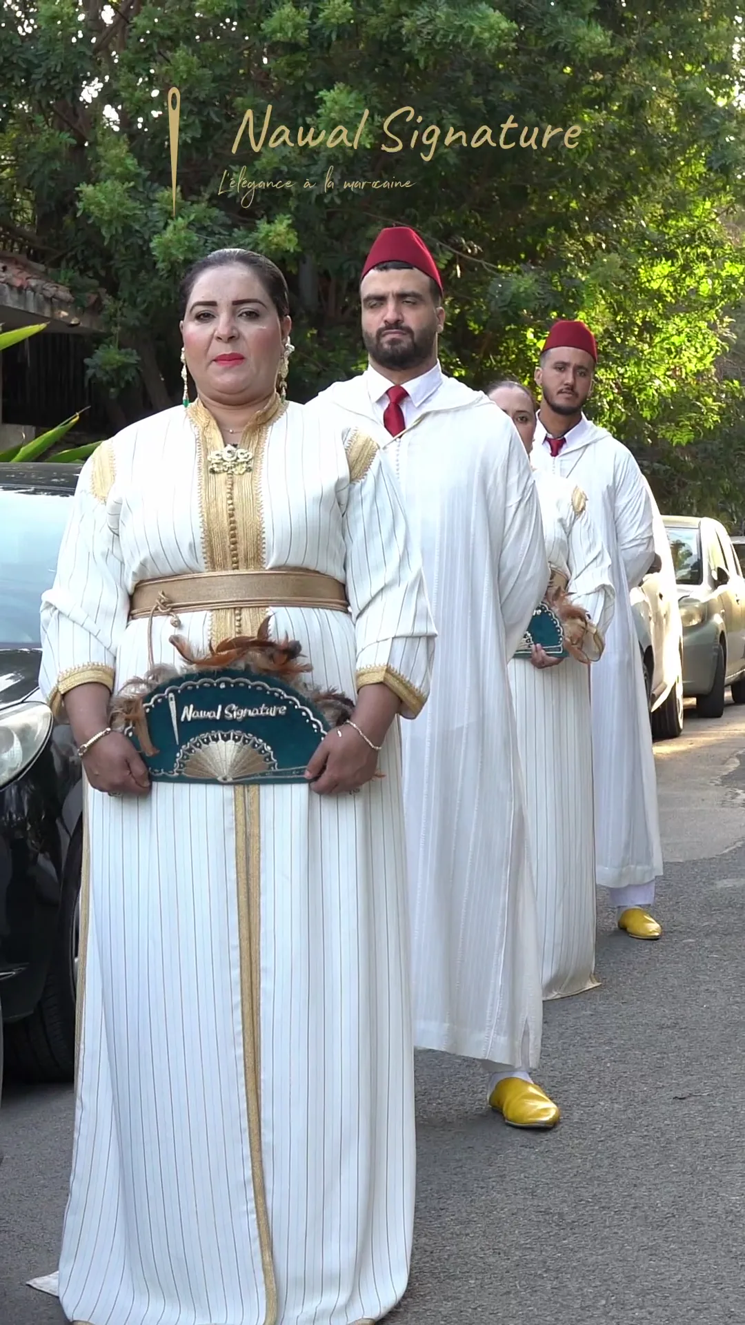 Cortège en caftans blancs et dorés marchant vers l’objectif