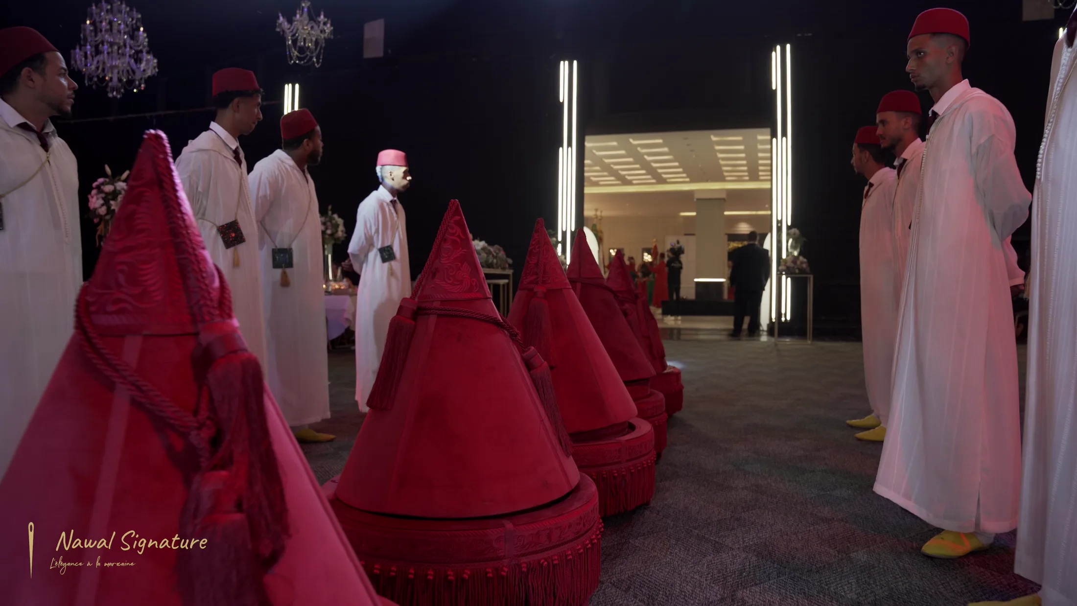 Rangée de Tyafer en velours rouge portés par des porteurs en djellaba blanche et fez